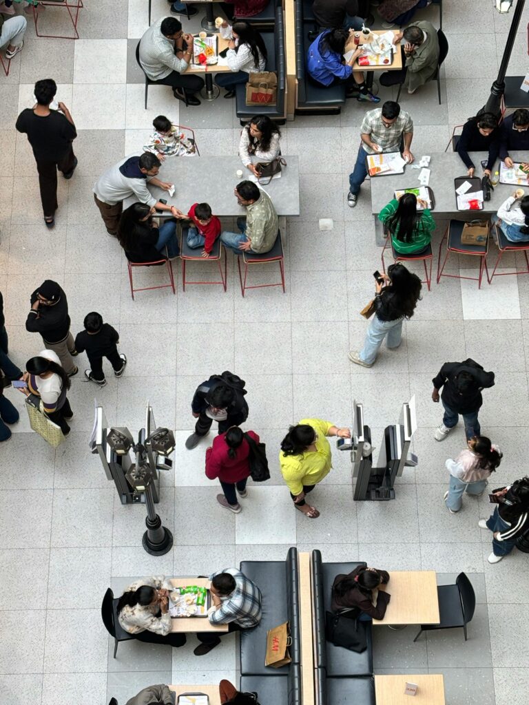 Top-down view of a bustling food court with people dining and walking.